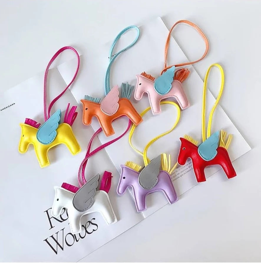Six charms cheval ailé colorés posés sur des magazines