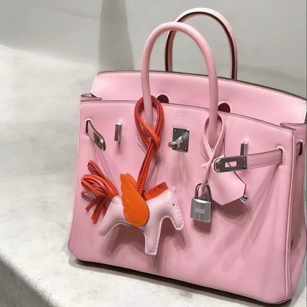 Charm cheval ailé rose et orange accroché à un sac rose